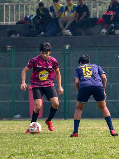A player skillfully shields the ball from a defender, demonstrating strength and composure under pressure.