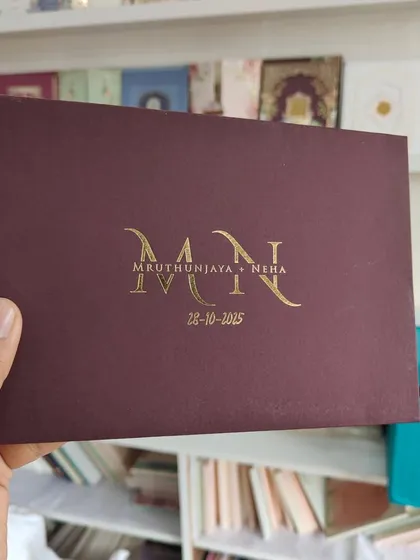 This invitation showcases minimalist luxury. The deep portwine envelope with a textured finish is personalized with the couple's monogram in brilliant gold foil, proving that sometimes the most elegant designs are the most simple.