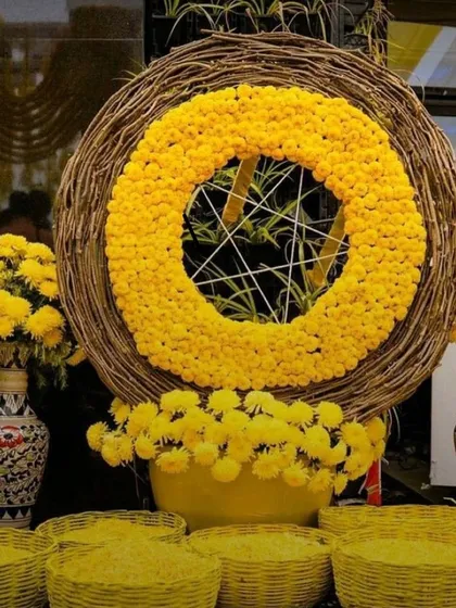 This unique Haldi decor piece features a large ring made of woven twigs, centered with a dense circle of yellow marigolds. It serves as a modern and rustic focal point for the event.