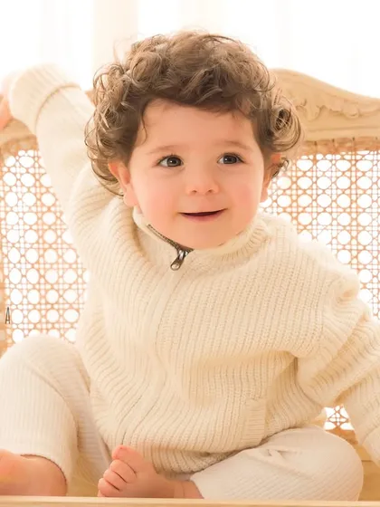 A portrait of a distinguished little gentleman. Milestone sessions are perfect for capturing your baby's budding personality, and this little one's curious and charming expression is simply unforgettable. The classic chair and soft lighting create a timeless feel.