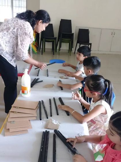 An instructor provides one-on-one guidance to children as they assemble photo frames from recycled materials, teaching both creativity and sustainability.