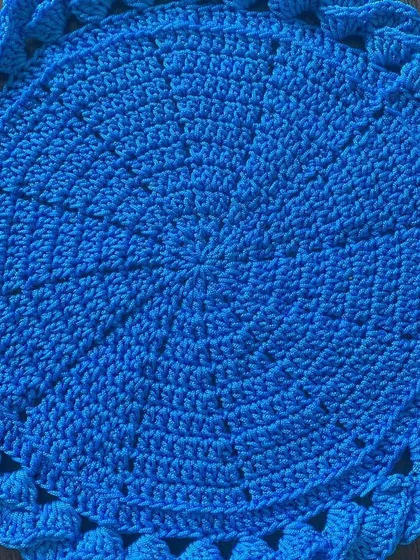 This vibrant blue placemat has a unique braided or woven border, giving it a lot of texture and visual interest.