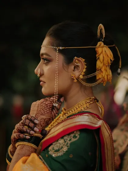 A classic profile shot of a Maharashtrian bride, showcasing her traditional jewelry, 'mundavalya', and intricate henna design.