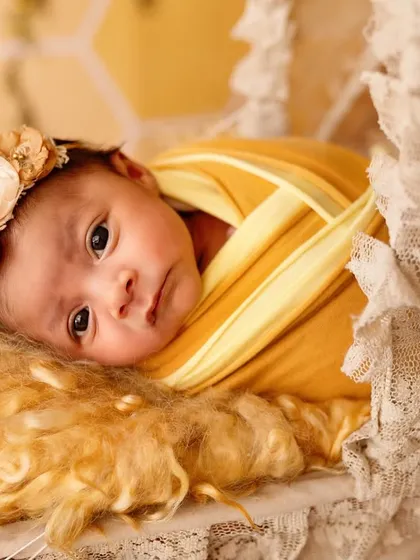A close-up of a newborn's face, peeking out from a cozy wrap. This shot highlights their delicate features and the peacefulness of a sleeping baby.