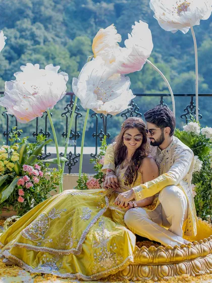 A beautiful portrait of the couple at their Haldi, framed by giant paper flowers. The unique decor and their happy expressions make this a truly memorable shot.