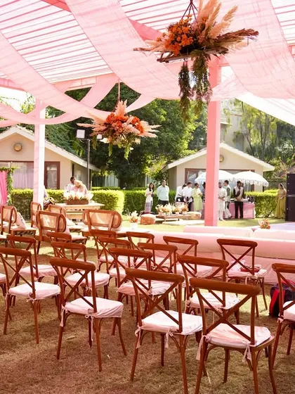 A wide view of the boho-chic Mehendi setup, showing the main stage, guest seating, and overhead decor. The cohesive design using pinks and natural textures creates a harmonious and stylish atmosphere.