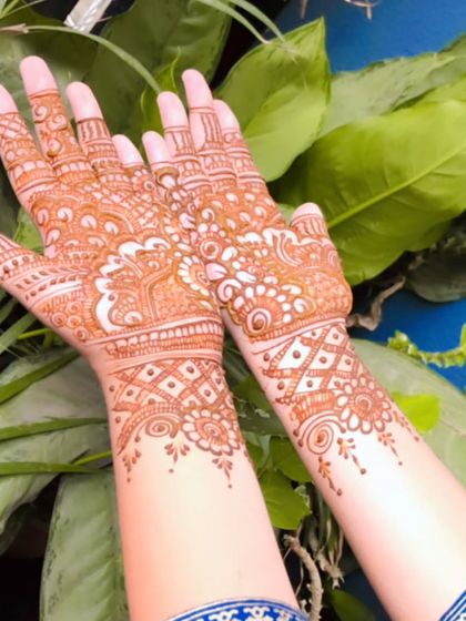 The beautiful orange-brown stain of a detailed Indian mehendi design, set against a background of lush green leaves. This shows the lovely color my organic henna produces.