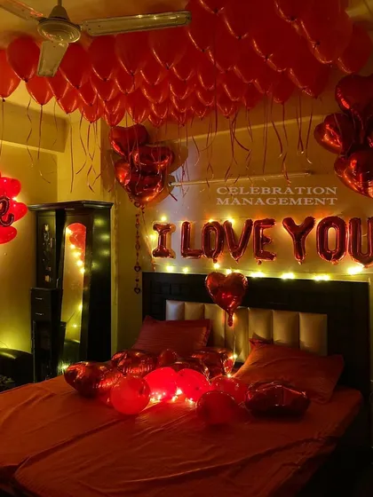 This is the ultimate romantic gesture. The room is bathed in a red glow from the lights and the sheer number of red balloons on the ceiling and bed, with 'I LOVE YOU' in lights as the centerpiece.