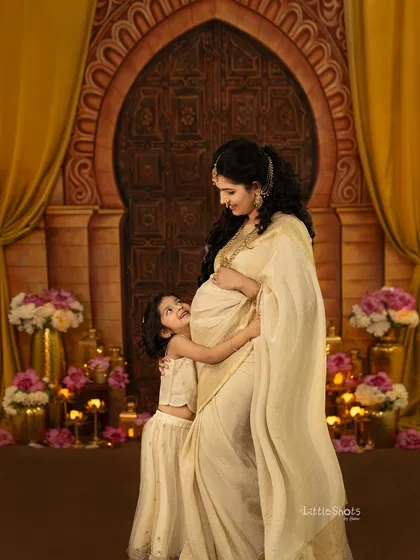 A truly magical moment between a mother and her daughter, eagerly awaiting the new arrival. This maternity session features an elegant, traditional theme with a golden backdrop, rich fabrics, and soft lighting to capture that beautiful pregnancy glow.
