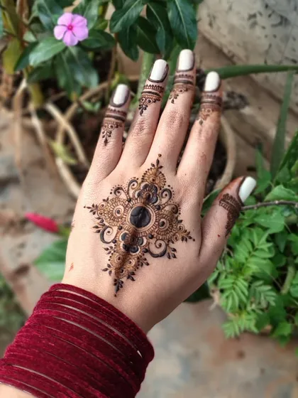 A chic and modern design on the back of the hand. The star-shaped mandala with a solid black center is very eye-catching and stylish.