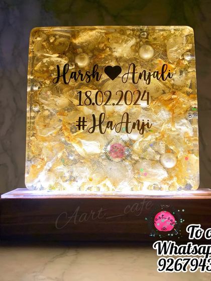 This square lamp, filled with golden preserved flowers and pearls, glows beautifully when lit. It's personalized with the couple's names, wedding date, and hashtag.