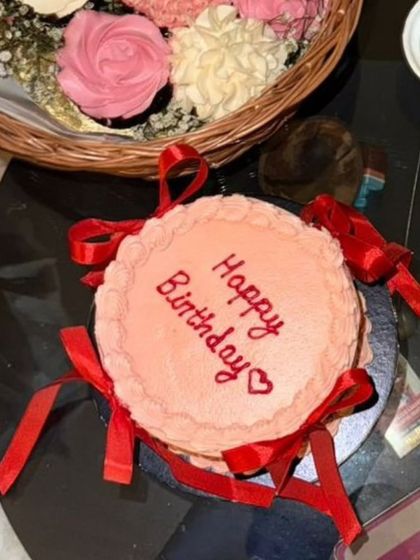 An overhead shot of the pink ribbon birthday cake, ready to be enjoyed. The "Happy Birthday" message is written with care, adding a personal touch.