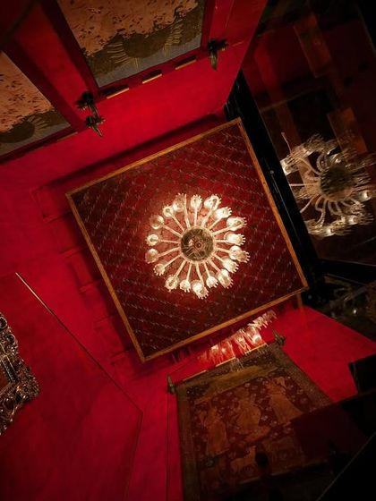 From our archives, 'The Big Door' is a retail space where tradition and modern design unite. This dramatic, upward-looking view captures the use of infinity mirrors and opulent chandeliers against a rich red backdrop, creating an illusion of endless elegance.