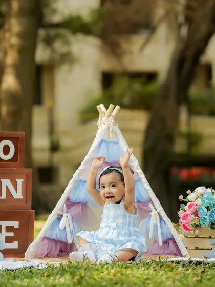 Celebrating a first birthday outdoors! This shot captures the pure happiness of a little girl enjoying the sunshine and our tent setup in a beautiful park setting.