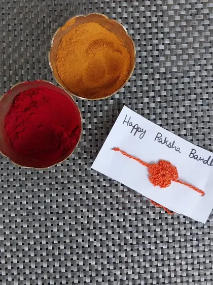 A simple flower-shaped rakhi in bright orange.