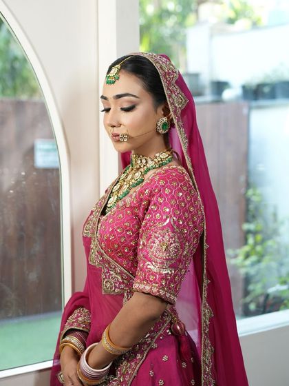 A side portrait of a bride, highlighting her soft glam makeup and neat floral bun.