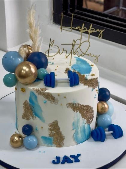 When strength meets sweetness. This fitness-themed cake is designed for the gym lover, featuring fondant dumbbells, abstract textures, and a cool blue and gold color scheme.