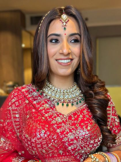 A happy bride ready for her reception. The soft curls and smoked-out eyes create a glamorous yet approachable look.