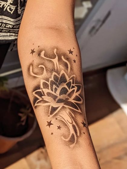 A striking black and white lotus tattoo created with an airbrush effect, surrounded by stars.