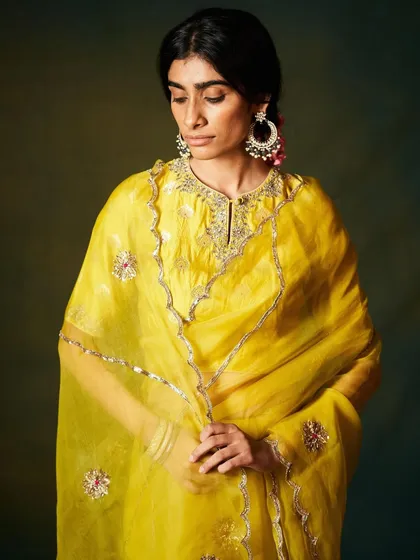A radiant yellow kurta set in sheer organza. The delicate silver gota patti work and floral motifs add a touch of shimmer to this sunny and cheerful ensemble.