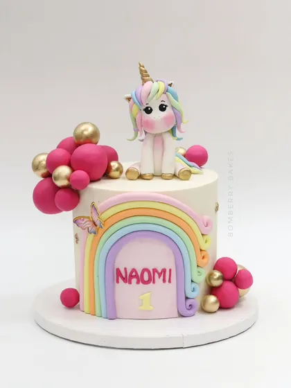 The full view of the pastel rainbow and unicorn cake, decorated with a cute fondant unicorn, a rainbow, and pink and gold spheres.