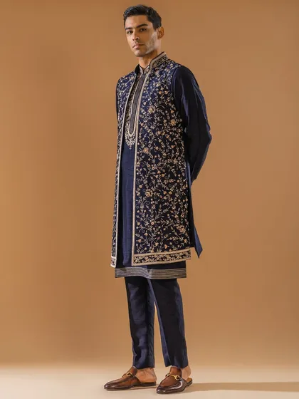 A masterful fusion of tradition and contemporary style, this layered Indo-Western ensemble in midnight blue is a statement of modern luxury. The long, exquisitely embroidered jacket over a classic kurta creates a dynamic silhouette for a sangeet or reception.