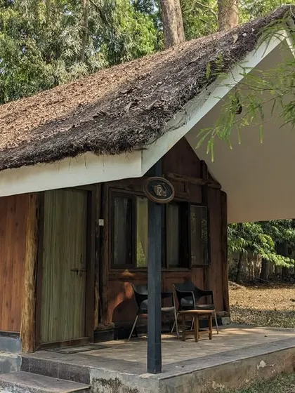 The charming exterior of a wooden cottage at the Dandeli camp, with a small porch for enjoying the forest ambiance.