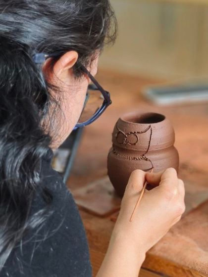 An artist carefully carves the details of an owl onto a pot. This sgraffito technique allows for precise line work and is perfect for creating illustrative designs on clay.