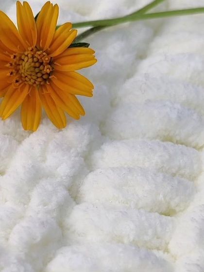 A close-up shot of the incredibly soft and plush white yarn used for the baby blankets, showing its fluffy texture.