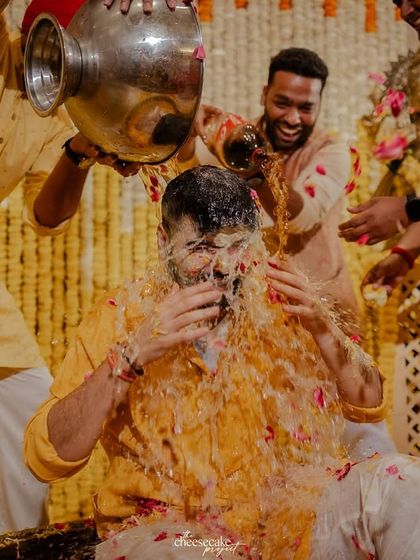 Another angle of the groom's Haldi, capturing his reaction as the water and petals come down.