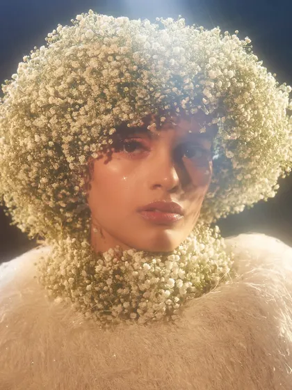 An avant-garde look where the model's hair and neck are completely covered in baby's breath, creating a stunning, high-fashion floral sculpture.