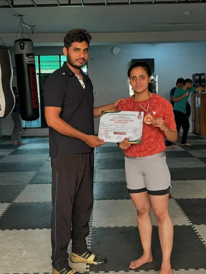 I am proud to stand with my student, Saniya Khan, as she holds her gold medal and certificate. This is a testament to her dedication and the effectiveness of our training program for competitive youth boxers.