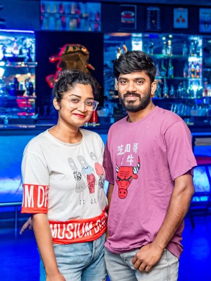 A couple posing in front of the vibrant blue bar.