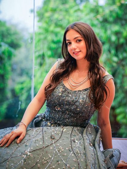 A full-shot of the grey ball gown, showcasing its beautiful flare and intricate sequin work against a lush green background.