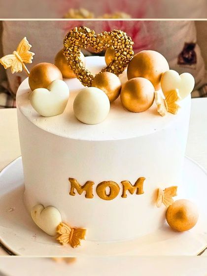 A beautiful "MOM" cake in white and gold, decorated with hearts and butterflies for a special mother.
