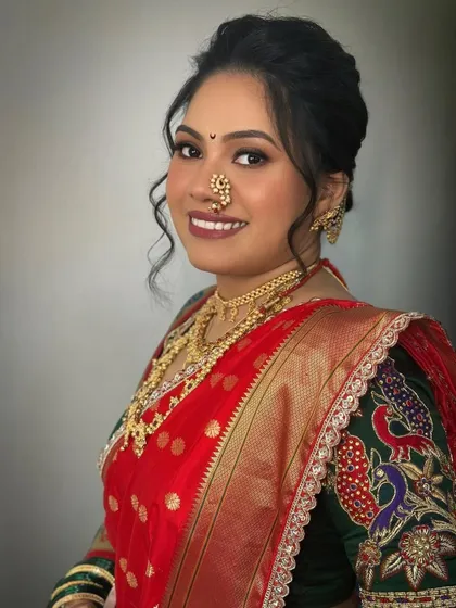 A portrait of my radiant Marathi bride, showcasing her elegant makeup and traditional red Paithani saree. The look is completed with a classic nath and gold jewellery.