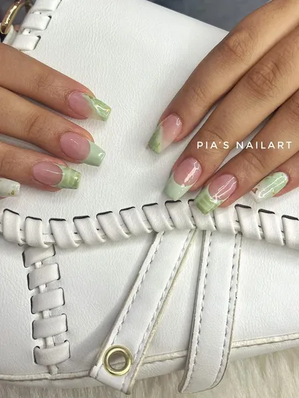 Pistachio green nails with a marble effect French tip. A unique and trendy color combination.