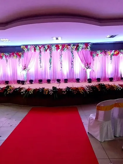 We use lighting and drapery to completely transform a venue. This stage features a soft pink backdrop with floral accents and a dramatic red carpet entrance for a grand reveal.