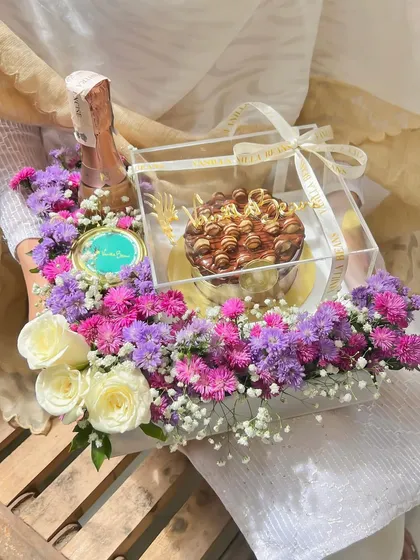 A top-down view of the luxurious Starlet Hamper, showing the balance of our rich chocolate bento cake, a mini champagne bottle, and a vibrant floral arrangement.