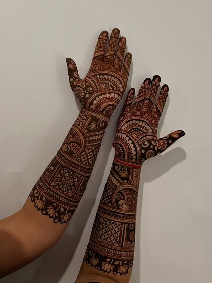 A classic design featuring symmetrical patterns on both hands. The layout includes bands of checks, florals, and traditional figures, perfect for a timeless bridal look.