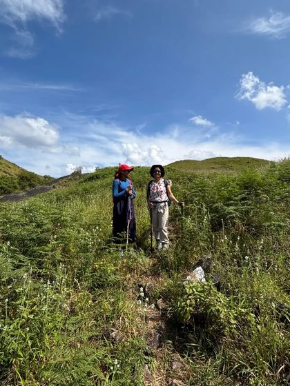 Two trekkers making their way through the tall grass.