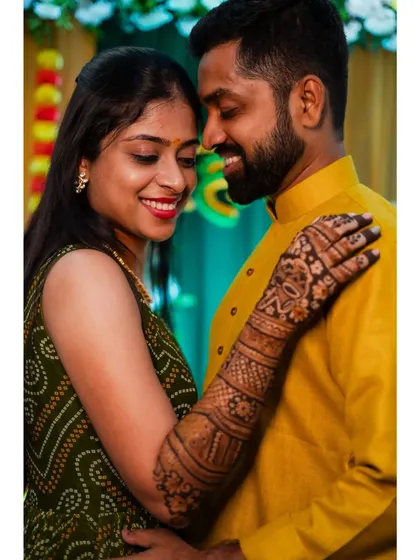 A sweet, smiling portrait of the couple at their mehendi ceremony. The bride's arm around her groom shows their close bond.