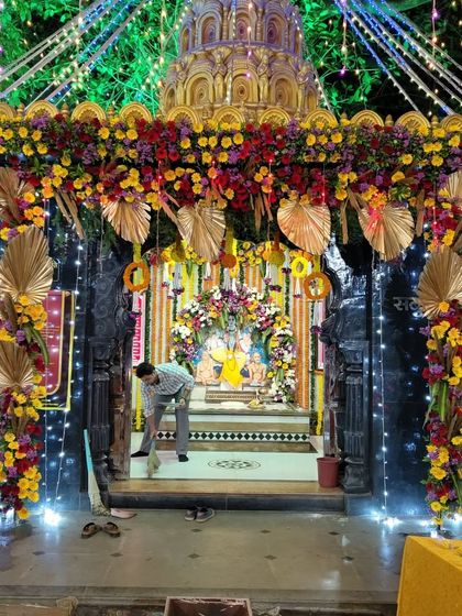 A nighttime view of our temple decoration, where we combined colorful flowers with golden palm leaves and fairy lights. This creates a magical and divine ambiance for evening prayers and events.