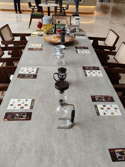 Our long communal table set up for a coffee workshop, showcasing various brewing equipment like a syphon and pour-over dripper.