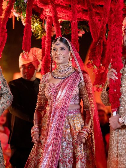 Natasha's bridal entry. Her radiant smile and the stunning burgundy and gold lehenga make for a breathtaking moment as she walks towards the ceremony.