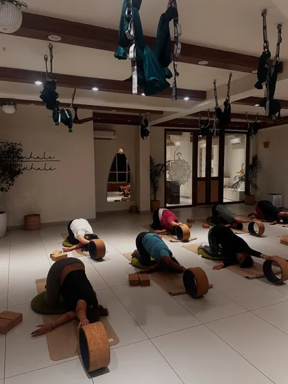 Students relax in a child's pose with the support of yoga wheels, a gentle way to end a challenging practice.
