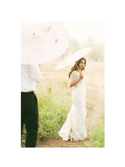 A soft, dreamy portrait of the bride holding a delicate parasol. The bright, airy feel of this photo gives it a timeless and ethereal quality, perfect for fine art wedding photography.