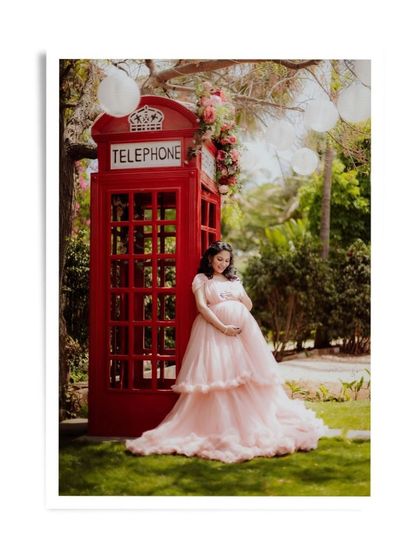 A beautiful maternity portrait by the red telephone booth, a whimsical and charming setting.