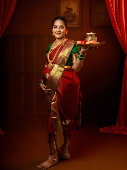 A graceful standing portrait of a mom-to-be in a nine-yard saree, holding a platter of offerings.