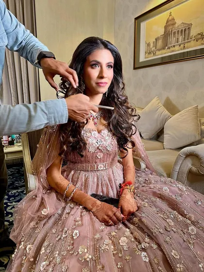 A candid moment during the getting-ready process. Even while the hair is being styled, you can see how the soft and glamorous makeup has already transformed her look.